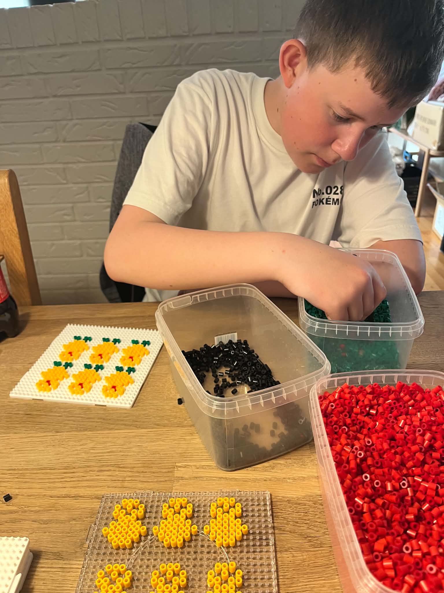 Jens lægger gule perler på en perleplade ved spisebordet